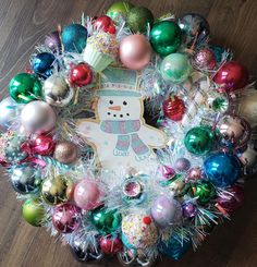 a wreath made out of christmas ornaments on a wooden floor