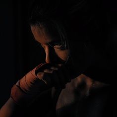 a woman in the dark holding her hands to her face and looking down at something