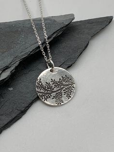 This beautiful circle silver necklace pendant has been entirely handmade using .999 fine silver. It has been cut from fine silver precious metal clay, textured, fired and oxidized. The pendant hangs from a sterling silver diamond cut cable chain. This unique and handmade necklace features an embossed floral leaf branch pattern. Pendant size: approximately 1/2 x 1/2 inches Chain length: adjustable at 16 and 18 inches can also be customized to whatever length needed The necklace is sent in a gift Boho Jewelry Bracelet, Precious Metal Clay, Leaf Pendant, Silver Pendant Necklace, Silver Diamonds, Silver Leaf, Fine Silver, Boho Jewelry, Handmade Necklaces