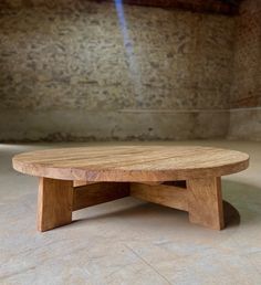 a wooden coffee table sitting on top of a floor next to a stone wall and window