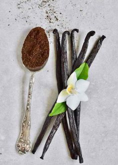 vanilla sticks and spoon with flower on white surface