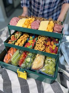 a tray filled with lots of different types of food on top of a table next to a person