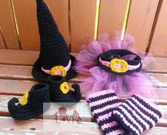 three crocheted hats and gloves are sitting on a wooden bench, one has a purple tulle