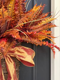 a basket filled with red and yellow leaves next to a black front door handle on a blue door