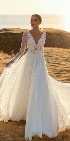 a woman in a wedding dress standing on the beach