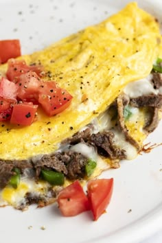 an omelet on a plate with tomatoes and meat