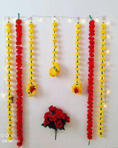 a bunch of flowers are hanging on the wall next to some string lights and beads