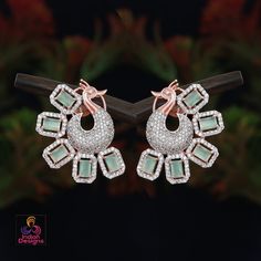 Emerald cut American diamond stone, peacock earrings in silver or rose gold background. Embellished with clear rhinestone crystals, the statement earrings is designed in a dancing peacock motif. Elegant Hand Set Rose Gold Earrings, Rose Gold Pierced Jewelry With Cubic Zirconia, Pierced Rose Gold Jewelry With Cubic Zirconia, Rose Gold Cubic Zirconia Pierced Jewelry, Elegant Hand-set Rose Gold Earrings, Elegant Rose Gold Hand Set Earrings, American Diamond Earrings With Elegant Design For Gift, Formal Peacock Design Drop Earrings, Rose Gold Earrings With Elegant Design For Party