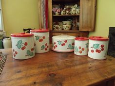 four canisters with cherries painted on them are sitting on a wooden table