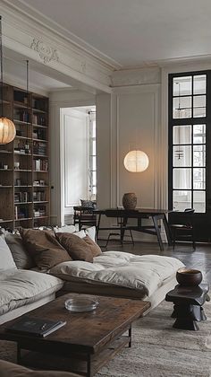 a living room filled with lots of furniture next to a book shelf full of books