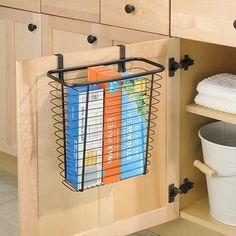 a kitchen cabinet with books on the shelf and a trash can in front of it