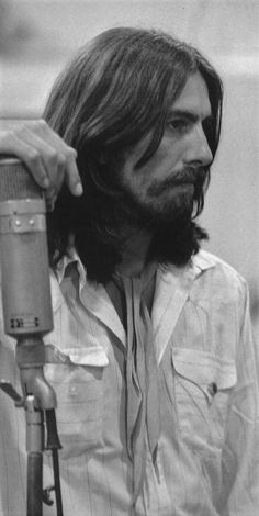 a man with long hair holding a microphone in front of his face and looking off to the side