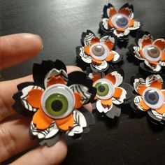 a hand holding several fake eyeballs in front of a black table with orange and white flowers