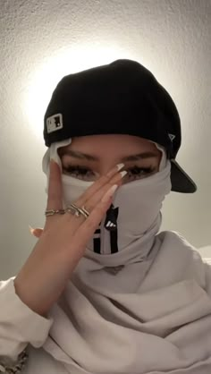 a woman wearing a black hat and scarf covering her face with a white bandana