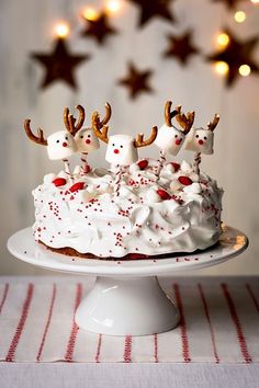 a cake with white frosting and red sprinkles decorated with reindeer heads