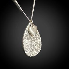 Our Fingerprint Jewelry is a personal and meaningful keepsake that will provide a constant reminder of your loved ones, whether they are with you in the present or present only in your memories. Simply provide us with the fingerprint and we will create a unique impression on a Sterling Silver Teardrop necklace, measuring approximately 7/8" in length. As an added touch, we also include a heart charm, measuring approximately 1/4". This necklace will be a cherished item for many years to come.   Our specialized process recreates your loved ones' fingerprints, providing a recessed texture that allows you to feel every intricate detail of the imprint.  OPTIONS:  ADD PERSONALIZED TEXT OR HANDWRITING ON REVERSE SIDE. Using our state-of-the-art infrared laser technology, we can expertly engrave th Teardrop Heart Charm Jewelry Gift, Teardrop Charms Jewelry For Anniversary, Personalized Teardrop Necklace For Memorial, Personalized Teardrop Memorial Necklace, Teardrop Engraved Necklace For Anniversary, Engraved Teardrop Necklace For Anniversary, Sterling Silver Teardrop Necklace For Memorial, Sterling Silver Teardrop Necklaces For Memorial, Heart-shaped Engraved Jewelry For Remembrance