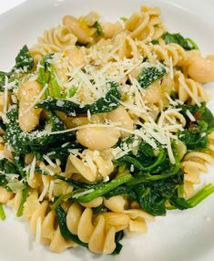 a white plate topped with pasta and spinach