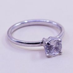 a close up of a ring with a diamond on the top and bottom, sitting on a white surface