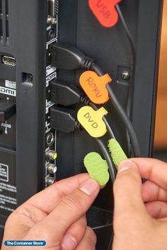 two hands are plugging into a server with wires attached to the back of it