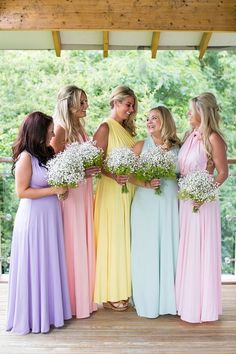 a group of women standing next to each other in long dresses and holding bouquets