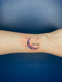 a small clock tattoo on the arm with stars and a crescent moon in the middle