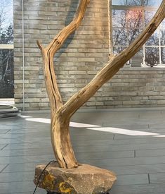 a wooden sculpture sitting on top of a stone slab in front of a brick building