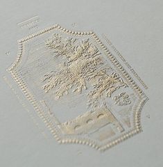 a close up view of a white paper with an ornate design on the bottom corner