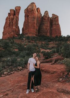 a man and woman standing in front of red rocks