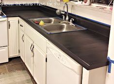 a kitchen with white cabinets and black counter tops, including a sink in the center