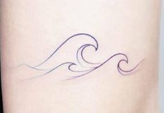 a small wave tattoo on the side of a woman's leg, with blue ink