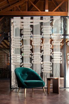 a green chair sitting in front of a window covered in white sheer curtains and chandelier