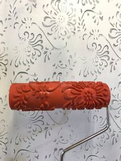 a red object is sitting on a metal stand in front of a floral wallpaper