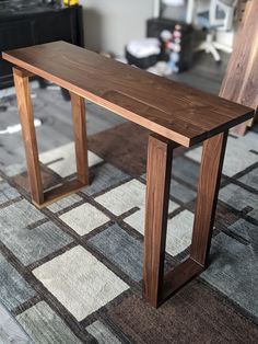 a wooden bench sitting on top of a carpeted floor next to a chair and table