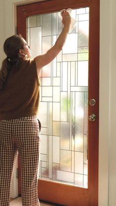 a woman is painting the glass on a door