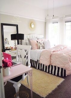 a bed room with a neatly made bed next to a desk and mirror on the wall