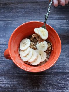 a person is eating cereal with bananas and oatmeal in an orange bowl