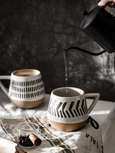 a person pouring water into a cup on top of a table