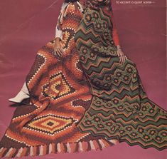 two women sitting next to each other on top of a pink floor covered in crocheted blankets