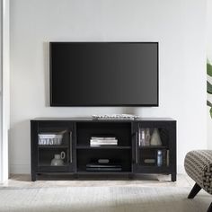 a flat screen tv sitting on top of a black entertainment center next to a chair