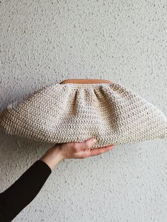 a hand holding a crocheted purse against a wall