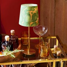 a table topped with bottles and glasses on top of a wooden table next to a lamp