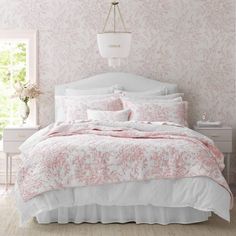 a bedroom with pink and white wallpaper and bedding