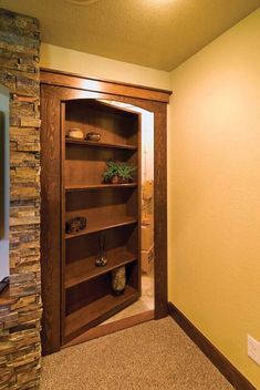 an empty room with a wooden bookcase in the corner and a stone wall behind it