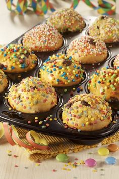 cupcakes with sprinkles are in a muffin tin on a table