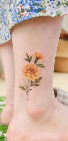 a woman's foot with yellow flowers on the bottom of her leg and an orange flower