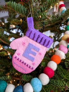 an ornament hanging from a christmas tree decorated with pom - poms