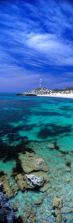 the water is crystal blue and clear with white sand on it's shore, near an island in the distance