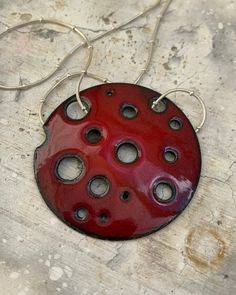 Although minimalistic, this enameled pendant is full of impact!  A 2-inch copper disc has had various sized circles cut out and enameled a bold fire engine red using a dark rich red enamel with a pop of bright red...  Copper edges fired during the enameling process were left black to give this pendant a slight organic look. This pendant is shown here with an 18-inch sterling silver chain (can also provide a similar chain in 16 inches, please message to see what other chain options are available) Red Enamel Round Pendant Necklace, Red Enamel Round Necklace, Handmade Red Enamel Necklaces, Handmade Red Enamel Necklace, Red Handmade Enamel Necklaces, Red Round Jewelry With Black Enamel, Red Enamel Jewelry With Large Pendant, Red Enamel Nickel-free Necklace, Red Enamel Nickel-free Necklaces