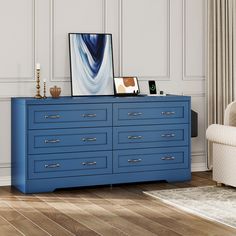 a blue dresser with two pictures on top of it and a chair in the background