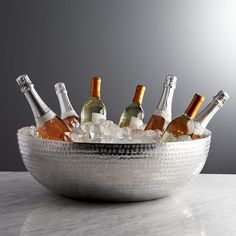 a silver bowl filled with bottles of wine on top of a white marble countertop